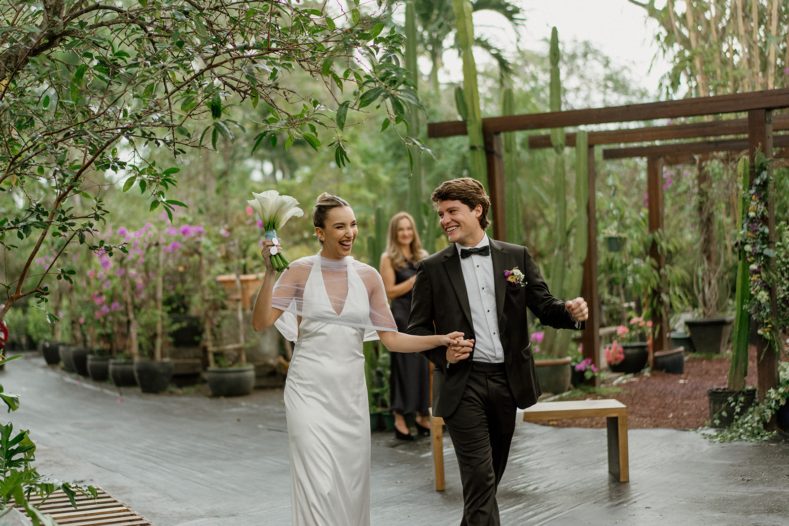 Bride laughs and holds bouquet while walking with groom