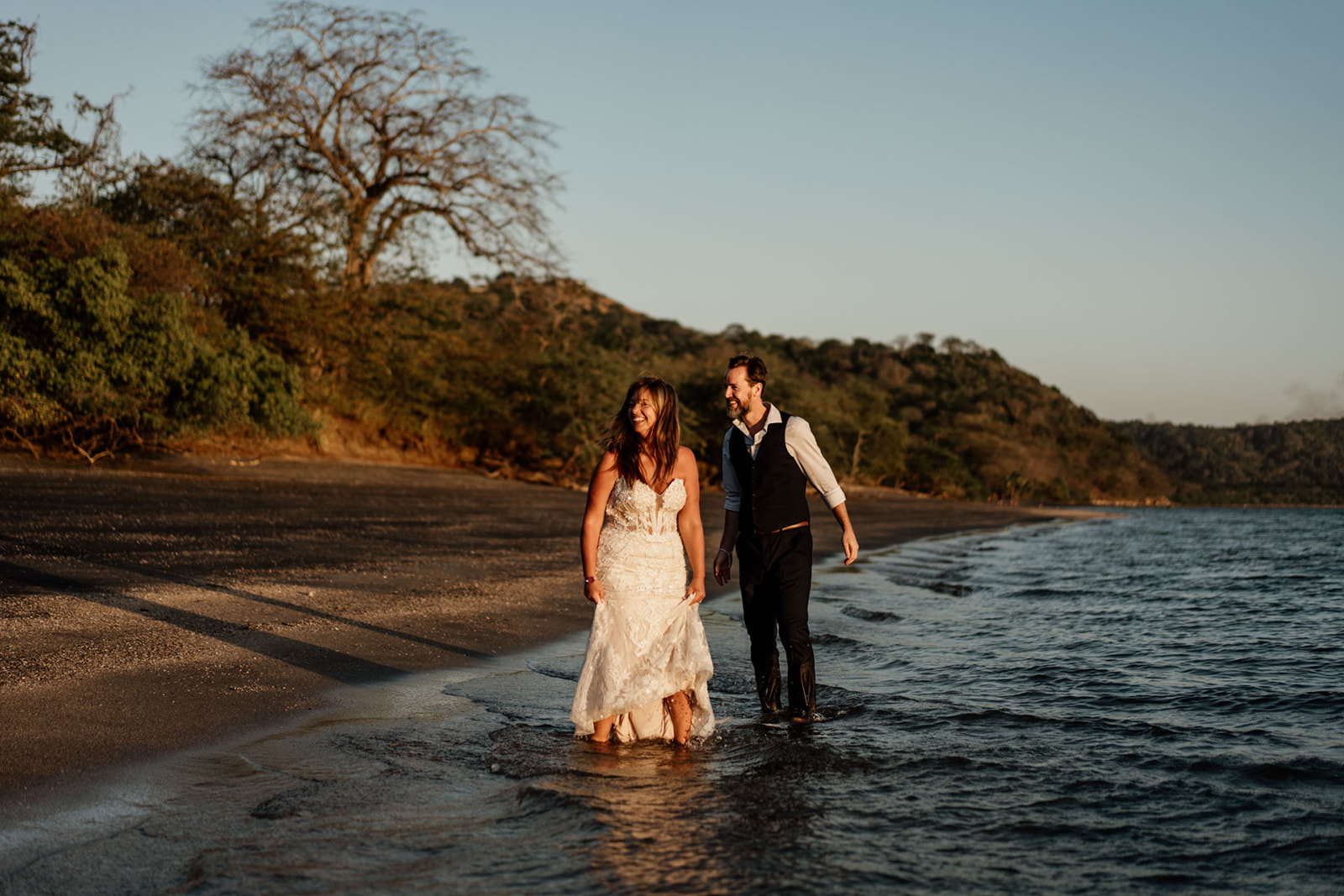 Bride and groom walking together in surf